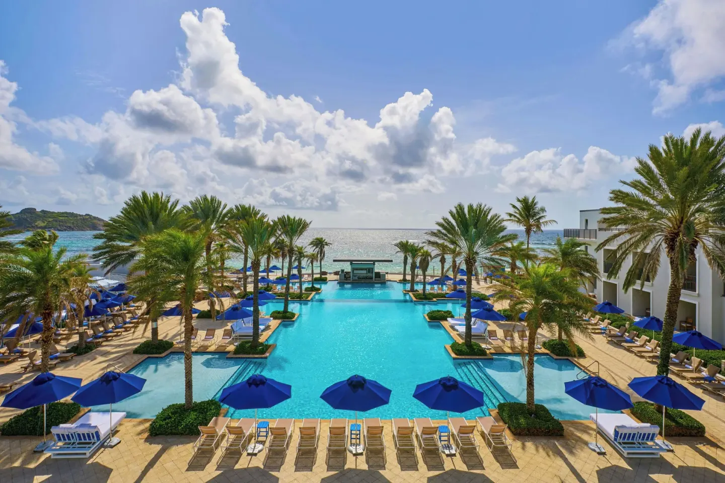 Elevated view of the palm-lined pool and ocean at JW Marriott St. Maarten Beach Resort & Spa.