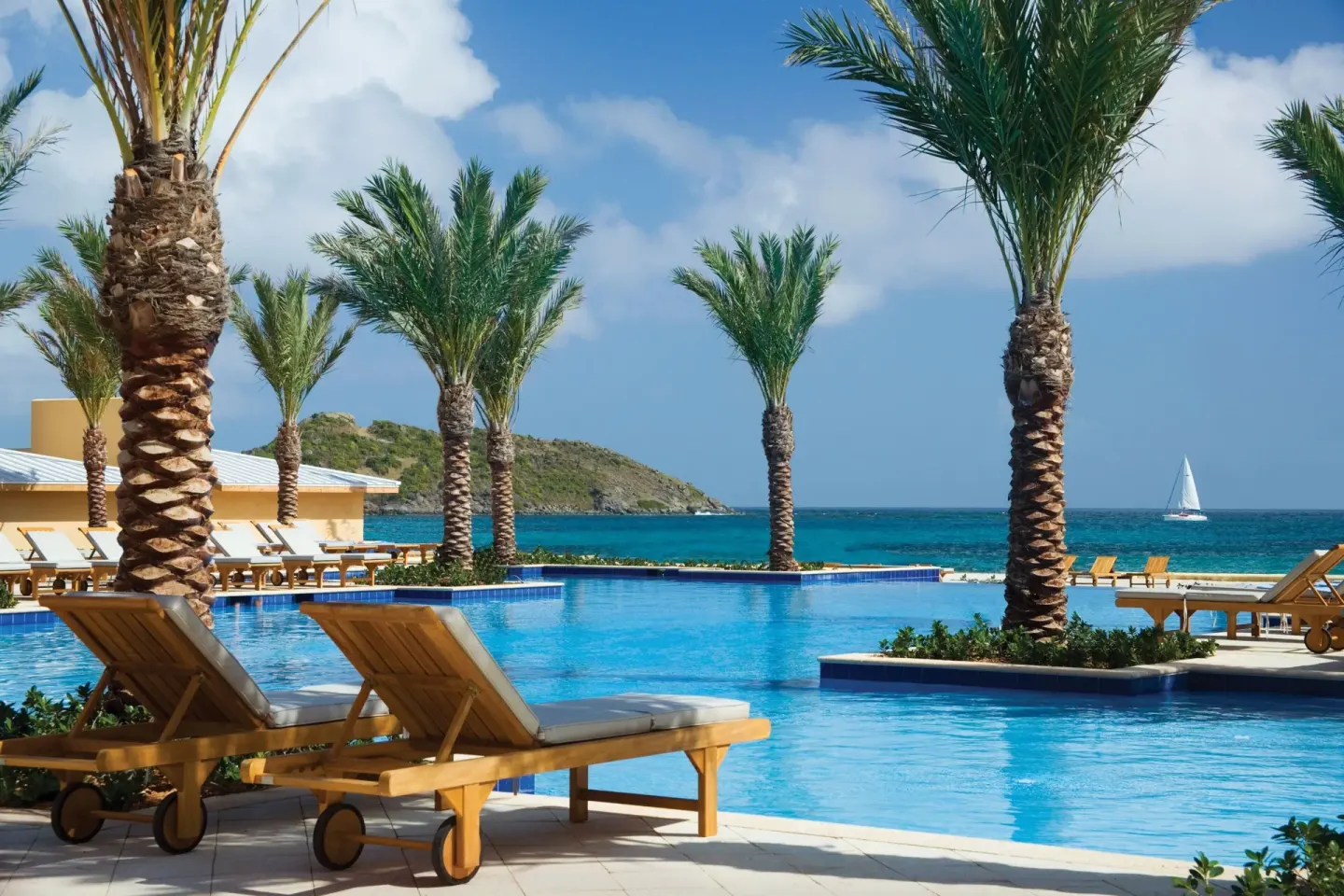 Pool with loungers, palms, and sea views at JW Marriott St. Maarten Beach Resort & Spa.