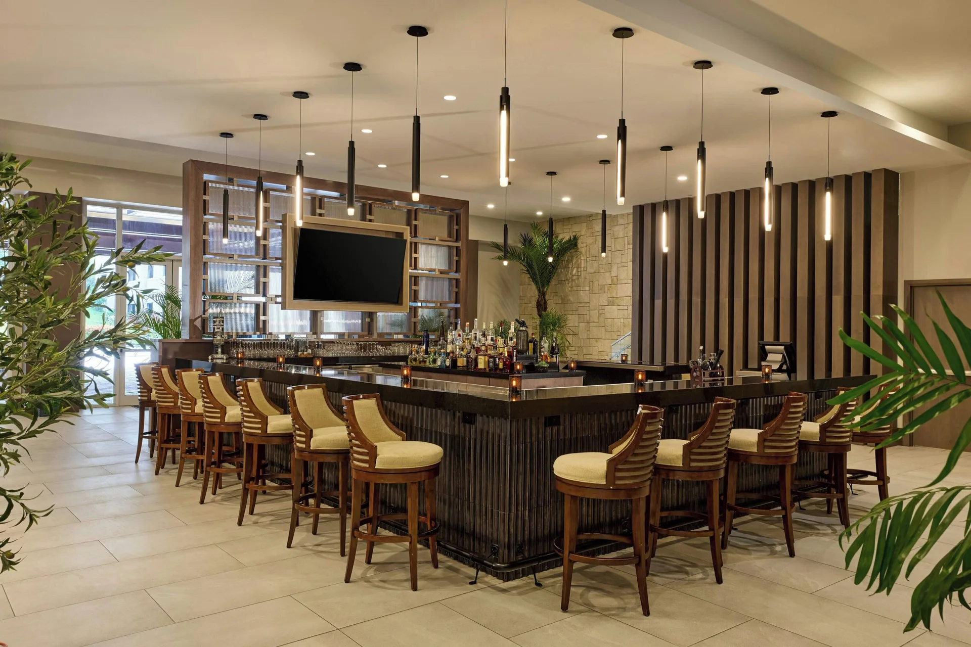 Lobby bar with wood stools and pendant lights at JW Marriott St. Maarten Beach Resort & Spa.