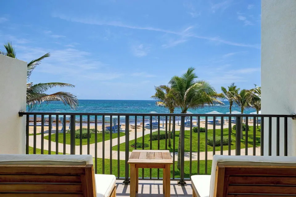 Oceanfront balcony seating at JW Marriott St. Maarten Beach Resort & Spa overlooking palms and sea.
