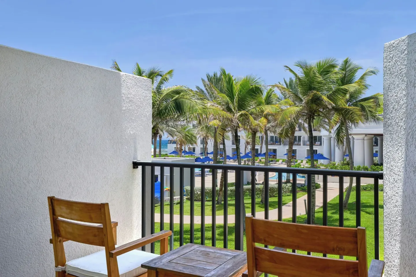 Furnished balcony with palm and pool views at JW Marriott St. Maarten Beach Resort & Spa.