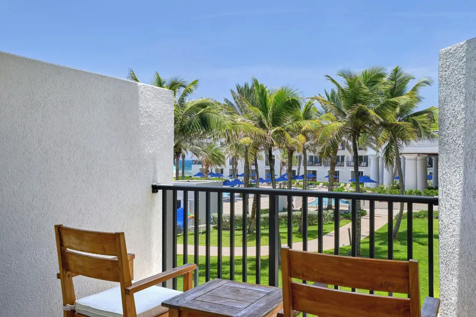 Furnished balcony with palm and pool views at JW Marriott St. Maarten Beach Resort & Spa.