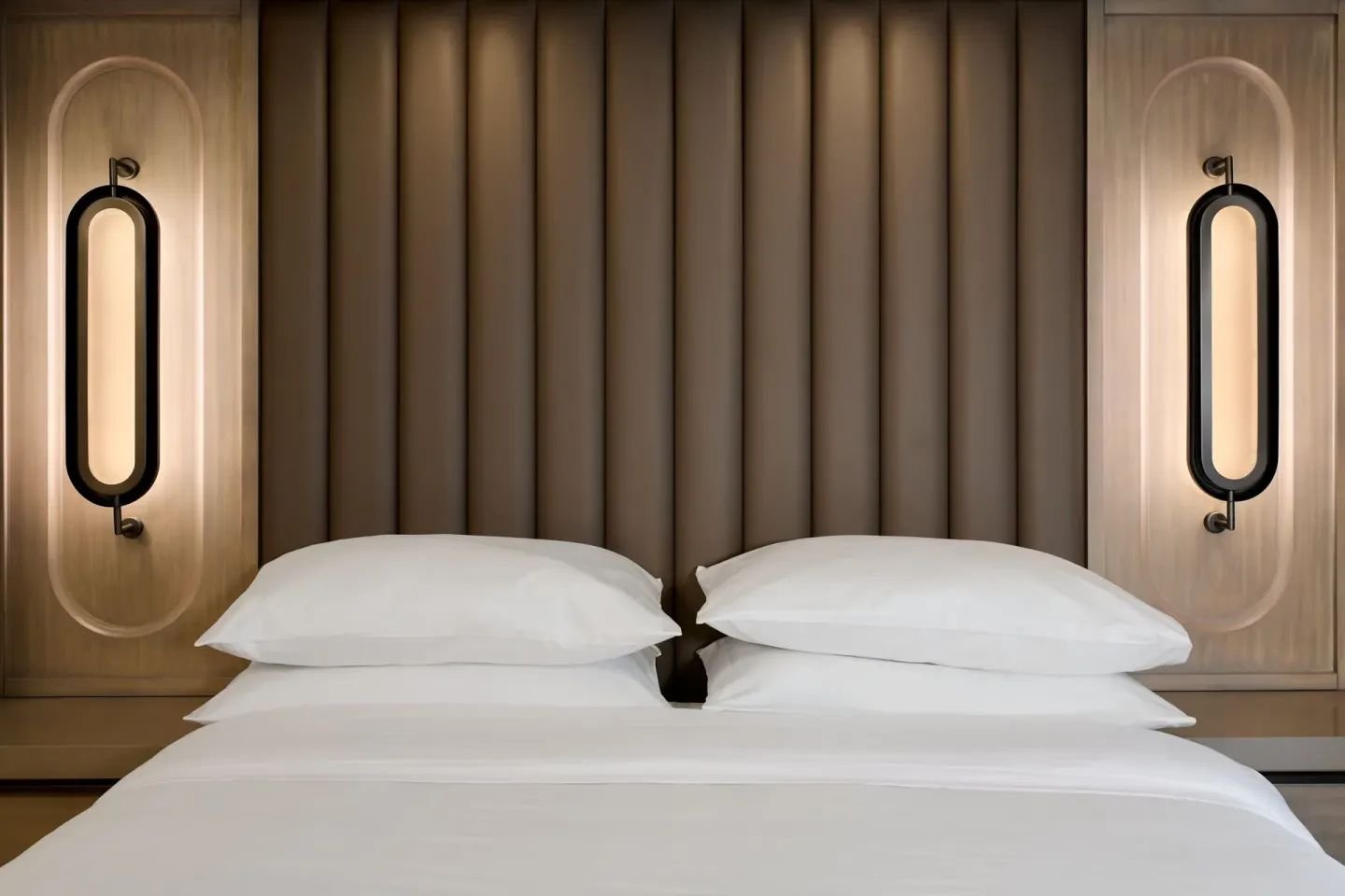 King bed with padded headboard and wall lights at JW Marriott St. Maarten Beach Resort & Spa.
