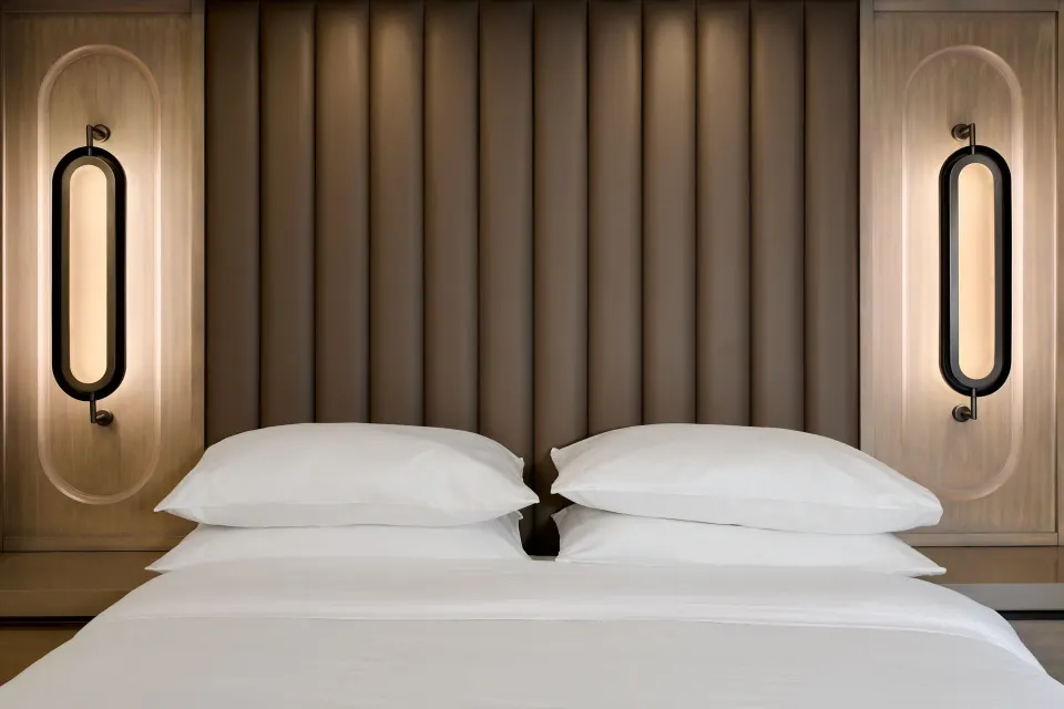 King bed with padded headboard and wall lights at JW Marriott St. Maarten Beach Resort & Spa.
