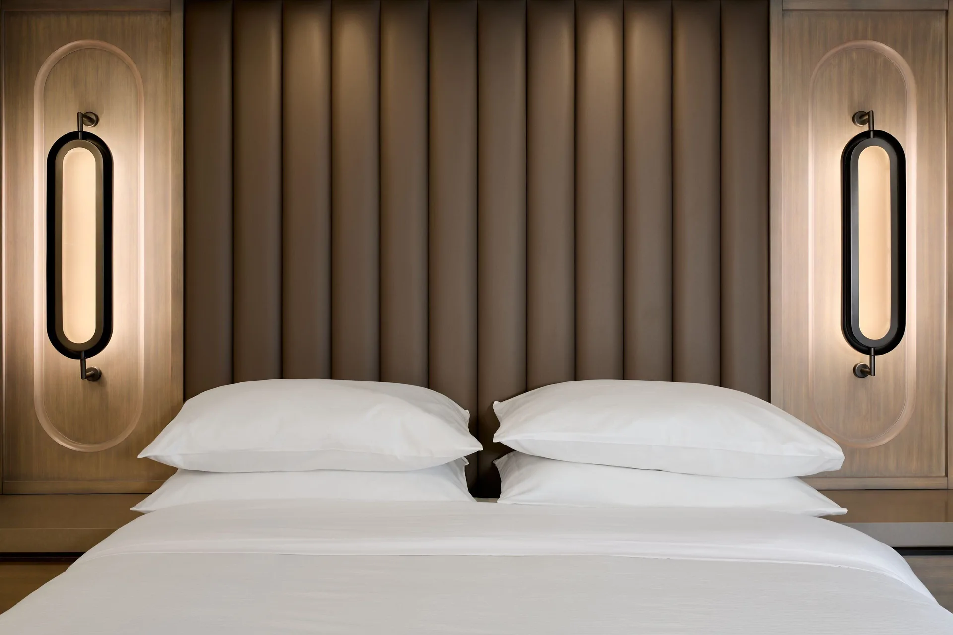King bed with padded headboard and wall lights at JW Marriott St. Maarten Beach Resort & Spa.