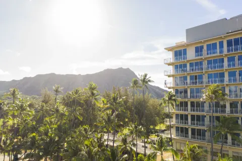 Hotel exterior, palm trees, and Diamond Head view at Kaimana Beach Hotel.
