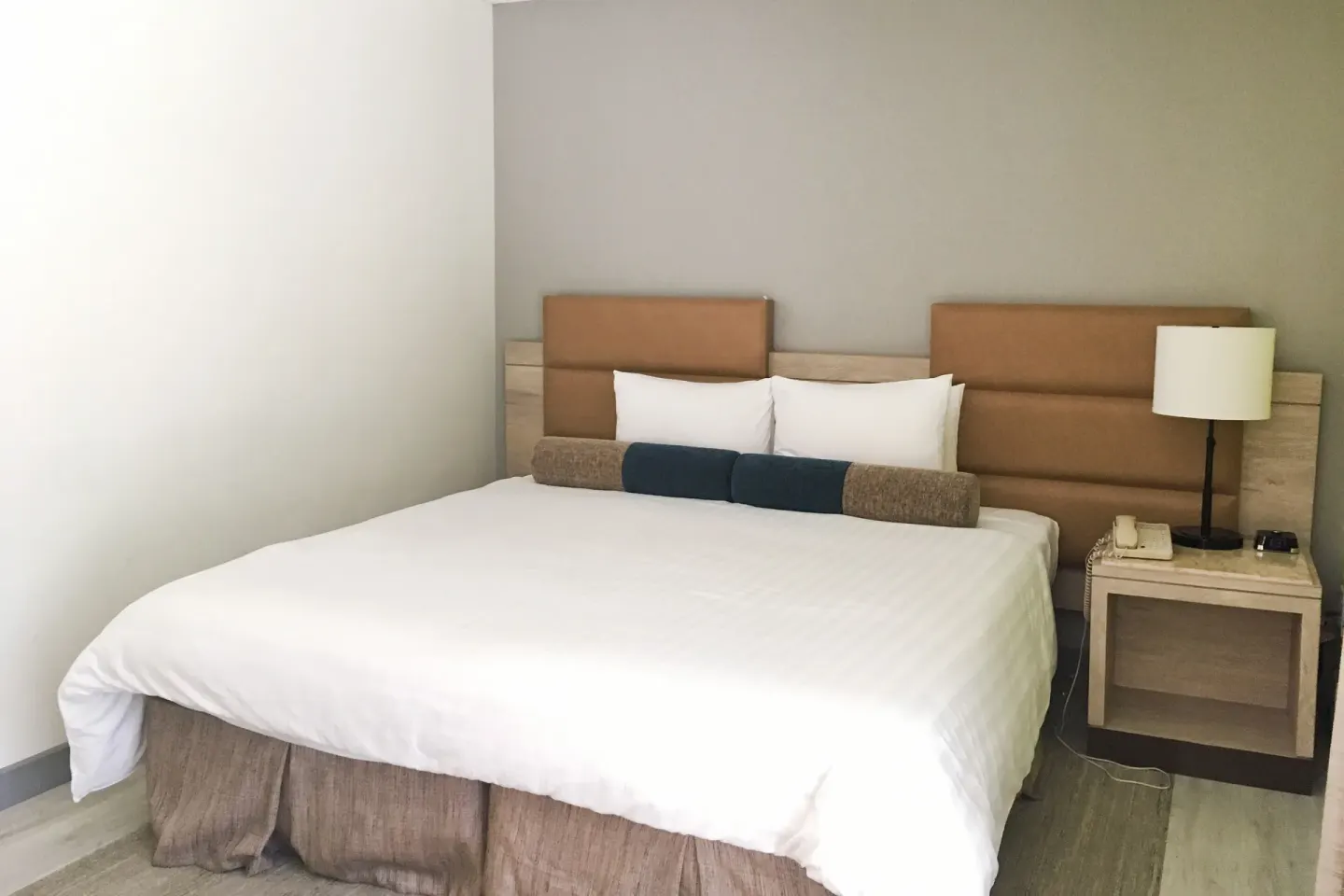 Guest room with a king bed, nightstand, and bedside lamp at Kaimana Beach Hotel.