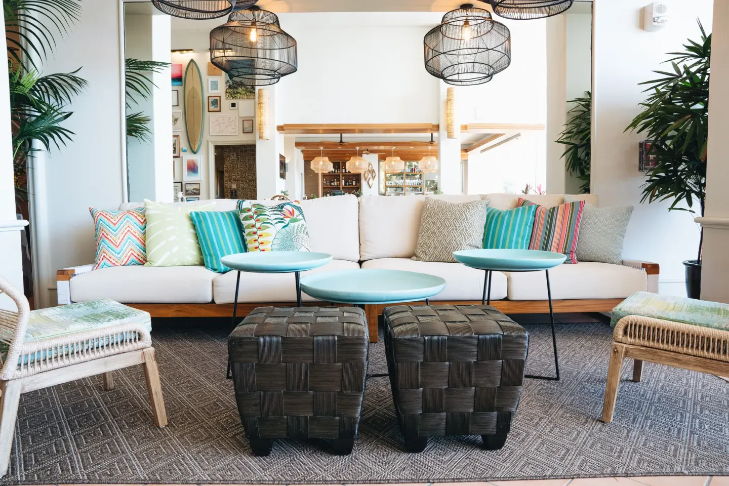 Lobby lounge with patterned pillows and woven pendant lights at Kaimana Beach Hotel.