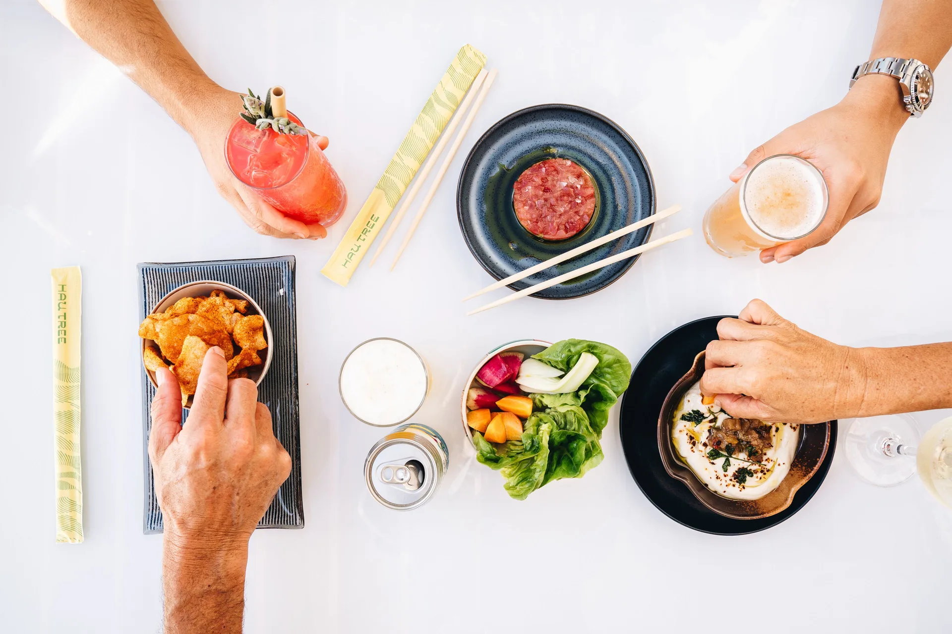 Overhead table of shared plates and drinks at Hau Tree at Kaimana Beach Hotel.
