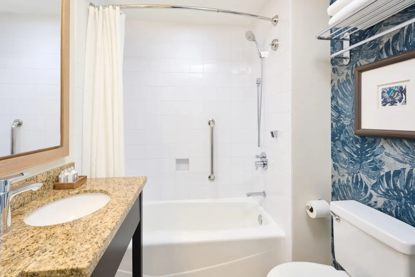 Classic Room bathroom with sink, tub-shower, grab bars, and blue patterned wall at Kaimana Beach Hotel.