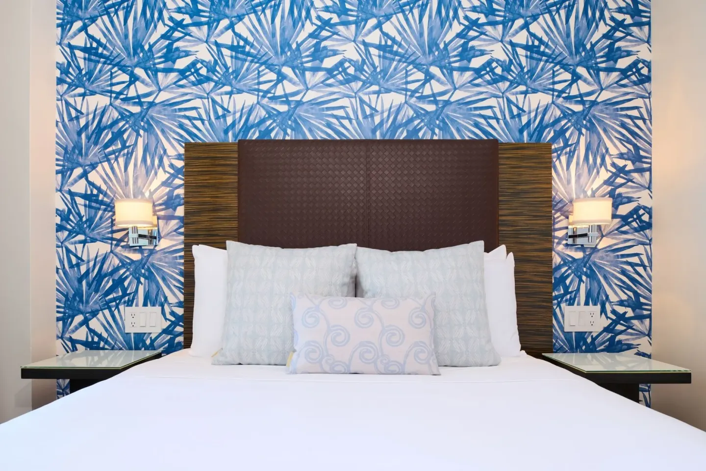 Classic Room king bed with blue leaf-patterned accent wall at Kaimana Beach Hotel.