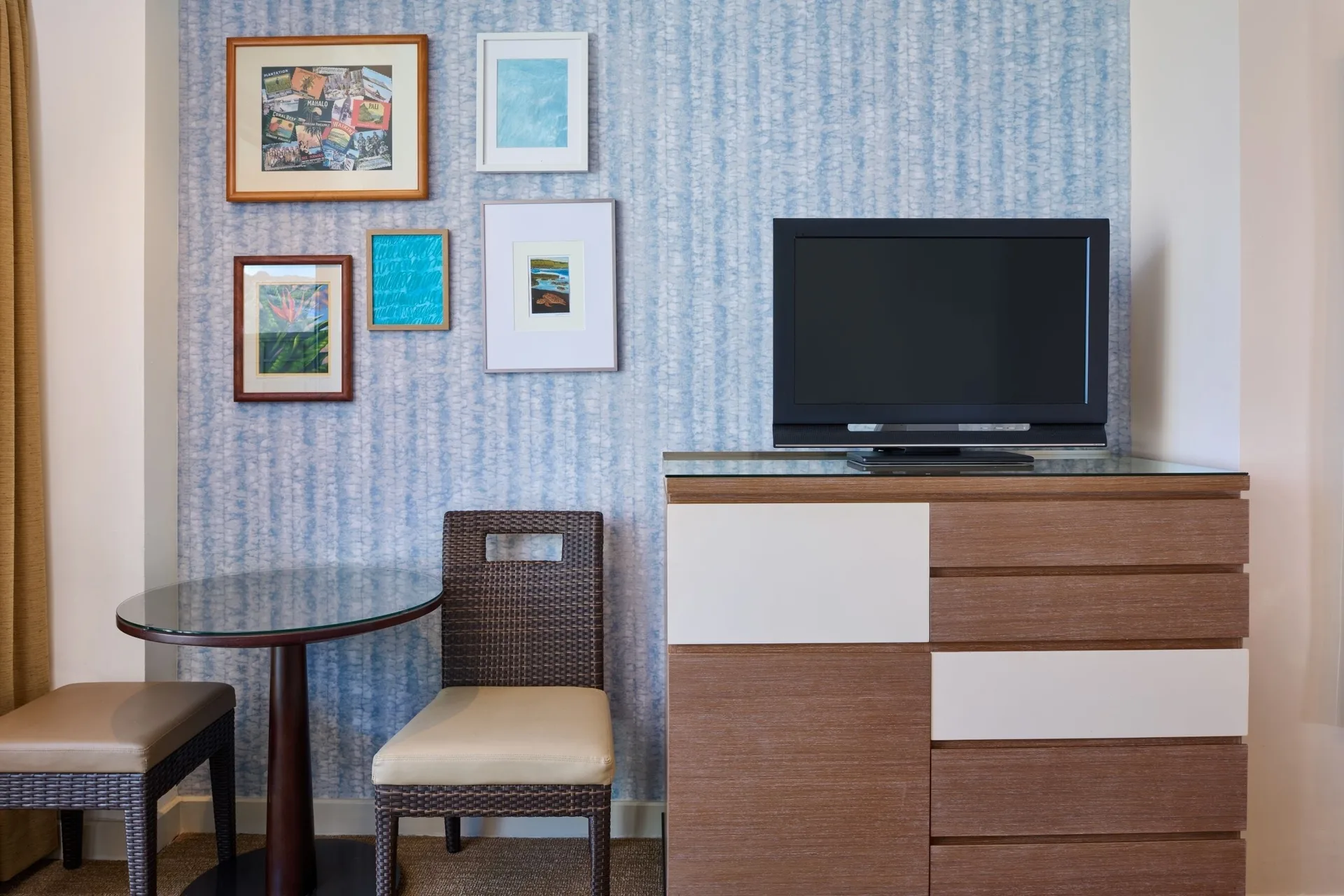 Classic Room sitting area with TV, dresser, table, and wall art at Kaimana Beach Hotel.