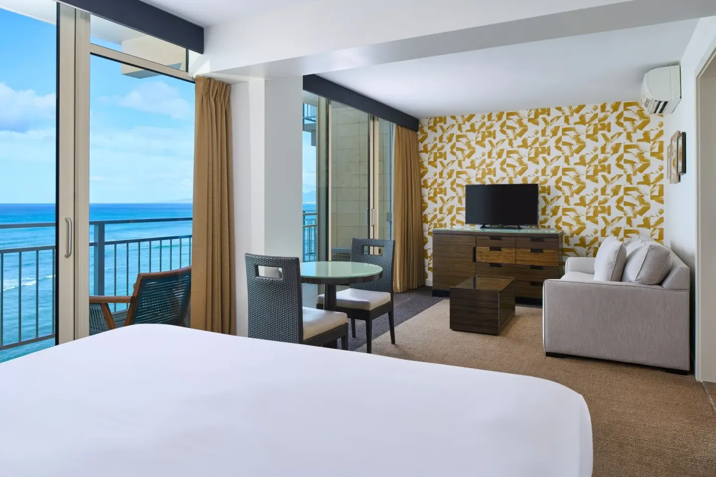 Junior Suite Oceanfront bed and sitting area with balcony ocean view at Kaimana Beach Hotel.