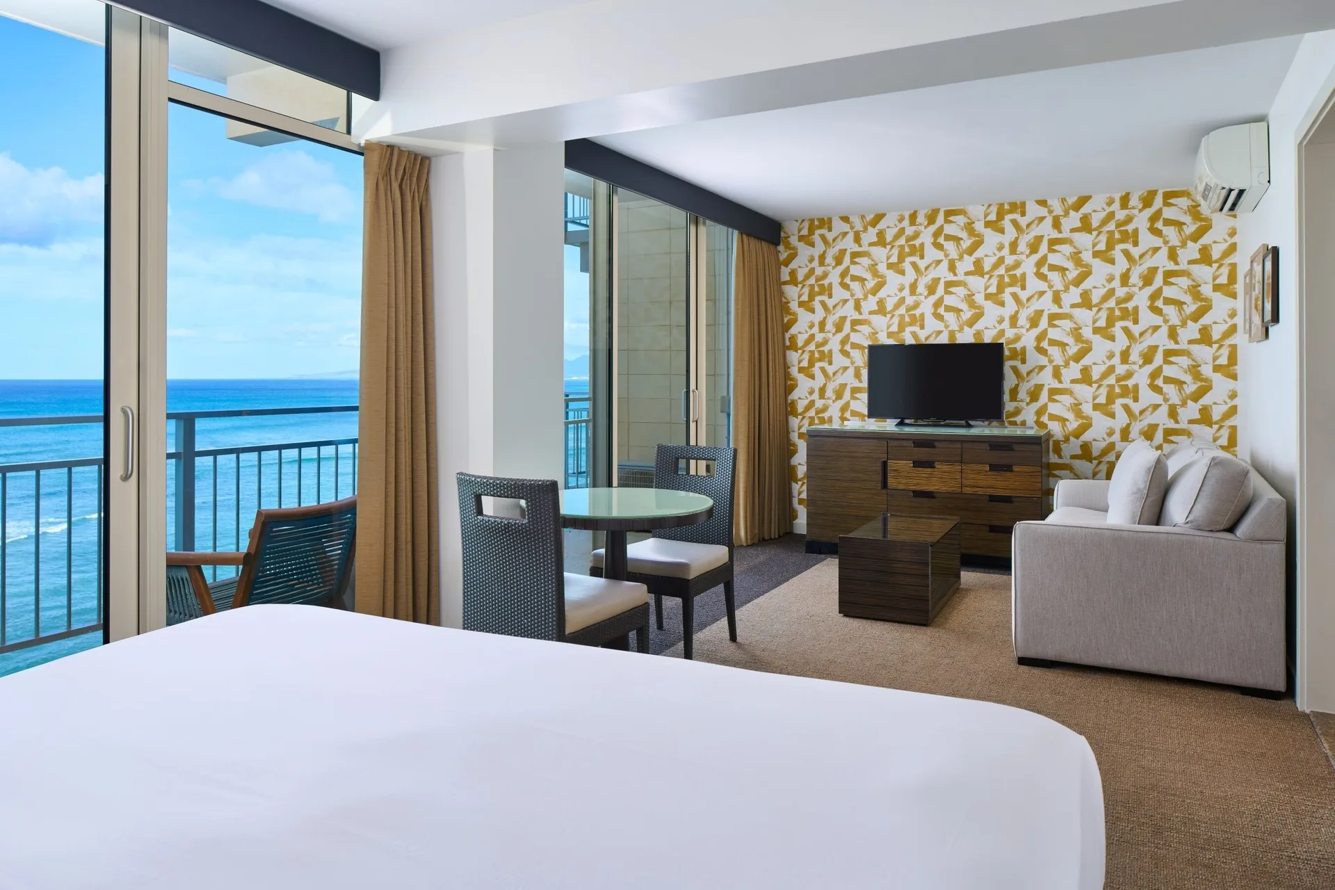Junior Suite Oceanfront bed and sitting area with balcony ocean view at Kaimana Beach Hotel.
