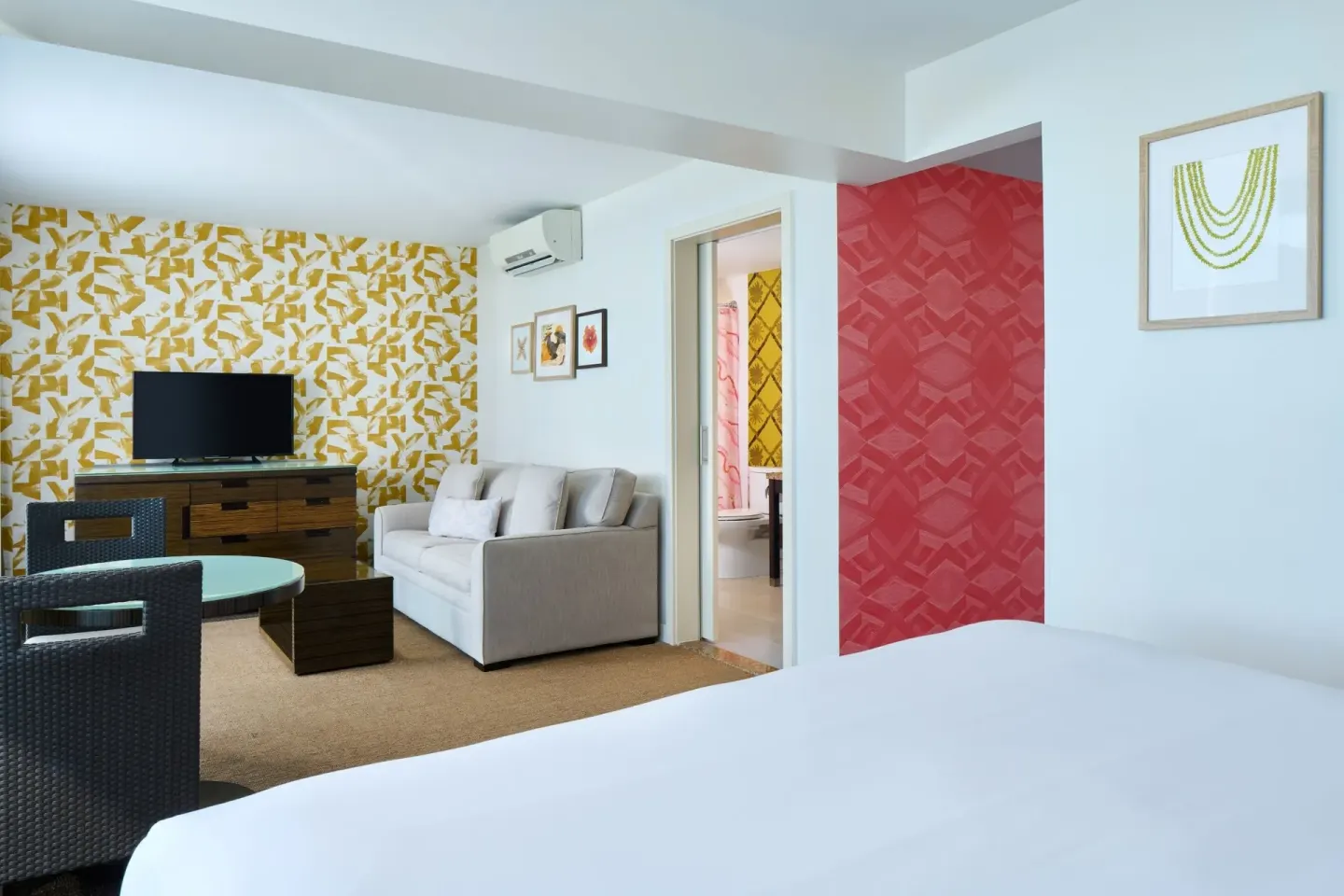 Junior Suite Oceanfront bedroom and lounge area with colorful walls at Kaimana Beach Hotel.