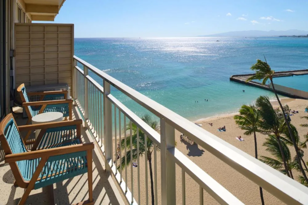 Ocean View room balcony with chairs above the beach at Kaimana Beach Hotel.
