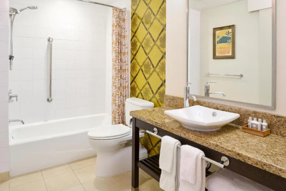 Ocean View room bathroom with tub, shower, and vanity at Kaimana Beach Hotel.