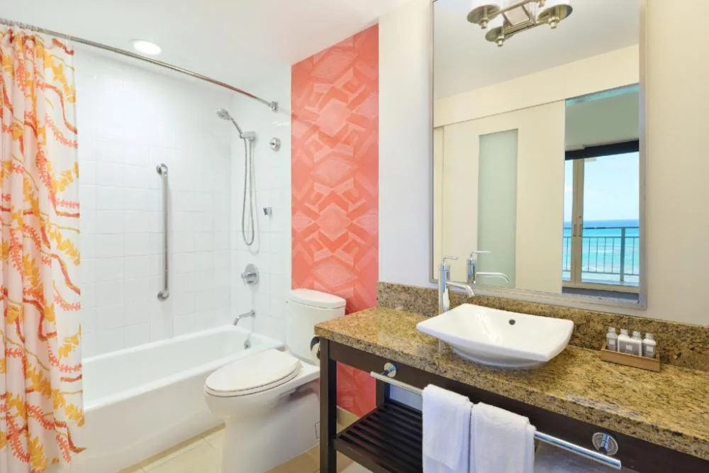 Oceanfront View Junior Suite bathroom with tub and vanity at Kaimana Beach Hotel.