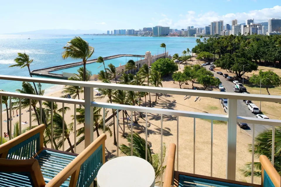 Ocean View room balcony with chairs overlooking Waikiki shoreline at Kaimana Beach Hotel.