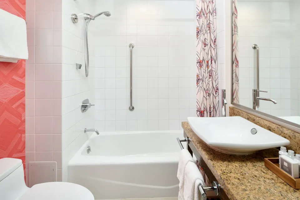 Ocean View room bathroom tub and sink with pink tile detail at Kaimana Beach Hotel.