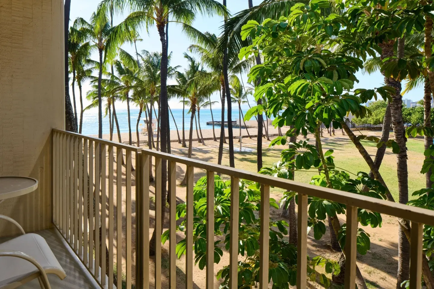 Park View room balcony with palms, lawn, and ocean beyond at Kaimana Beach Hotel.