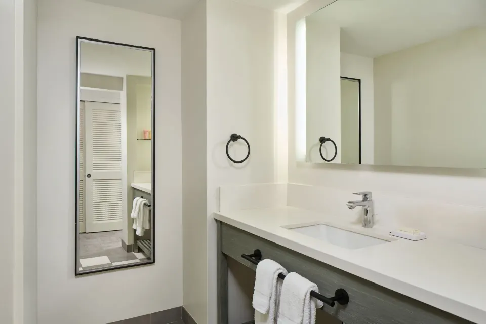 Park View room bathroom vanity with mirrors and towels at Kaimana Beach Hotel.