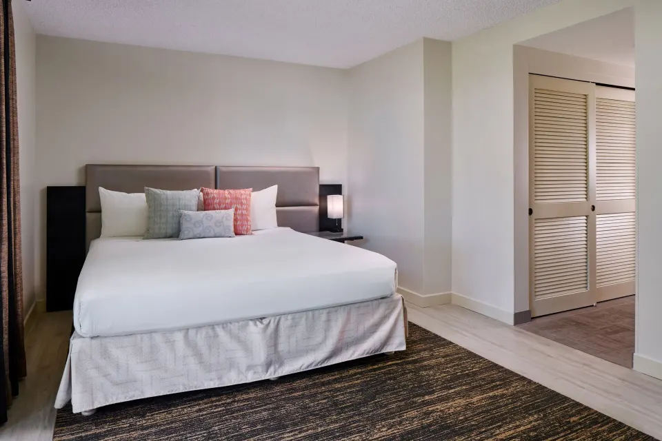 Park View room king bed with pillows and closet entry at Kaimana Beach Hotel.