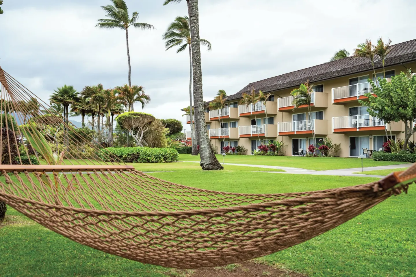 Hammock on a lawn facing guest-room balconies and palms at Kauai Coast at the Beachboy.