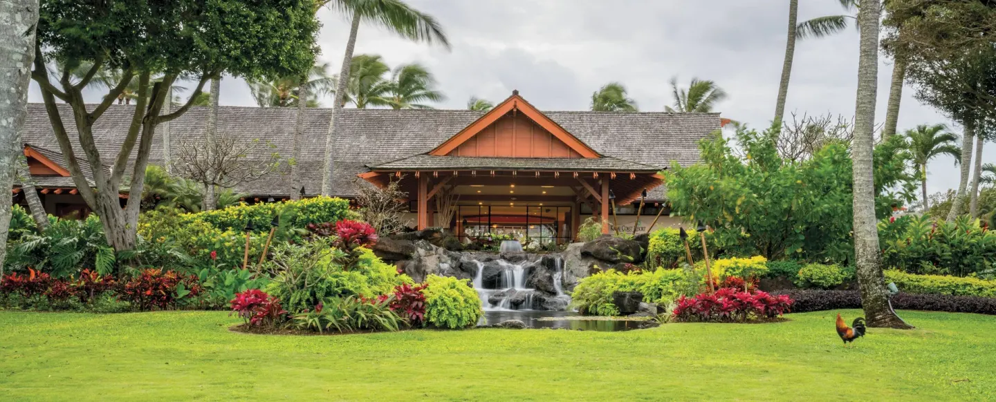 Lobby building with waterfall, gardens, and a rooster at Kauai Coast at the Beachboy.