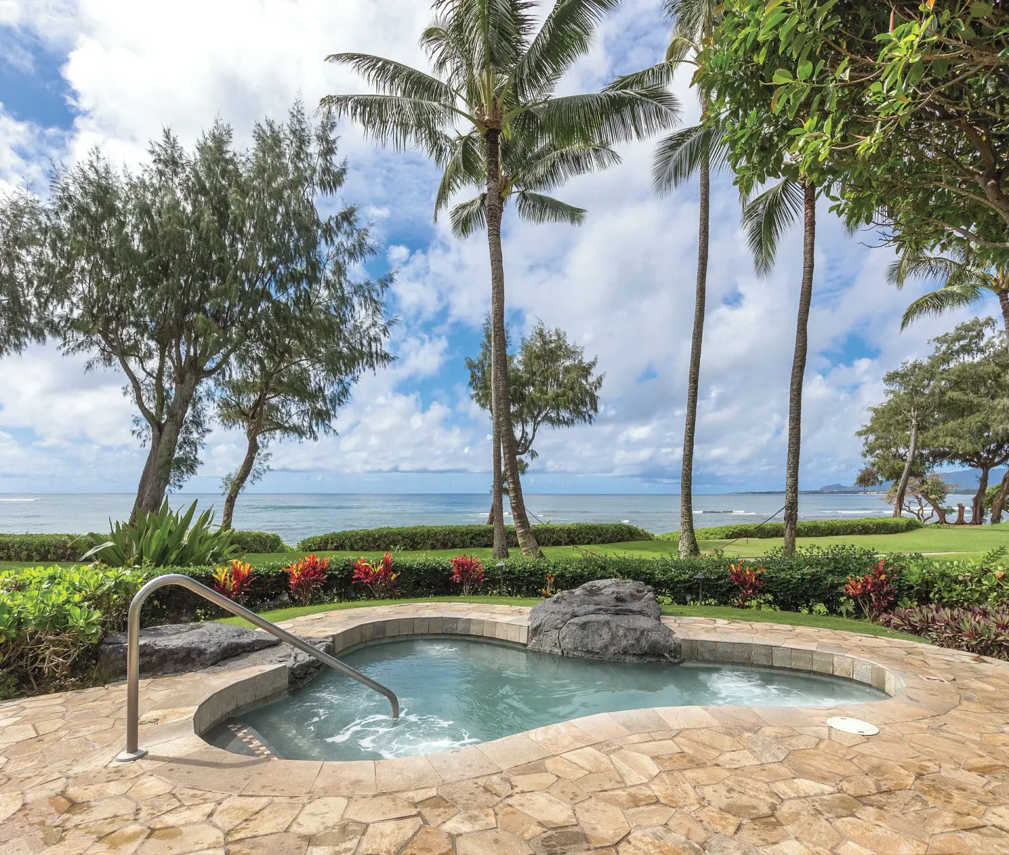 Oceanfront hot tub with palms and lawn at Kauai Coast at the Beachboy.