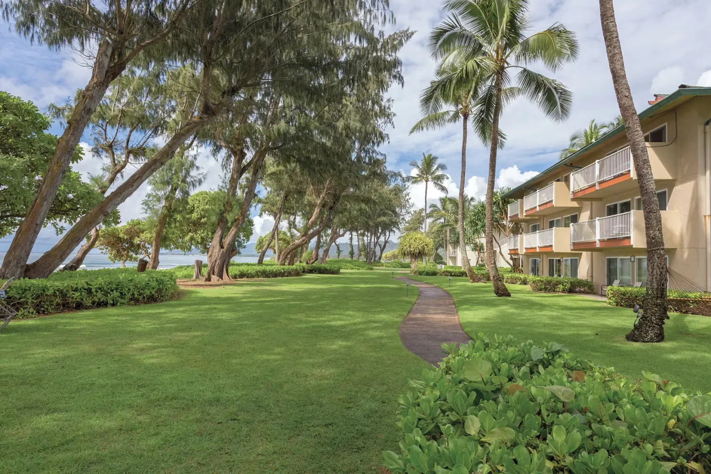 Oceanfront lawn, walkway, and balconies at Kauai Coast at the Beachboy.