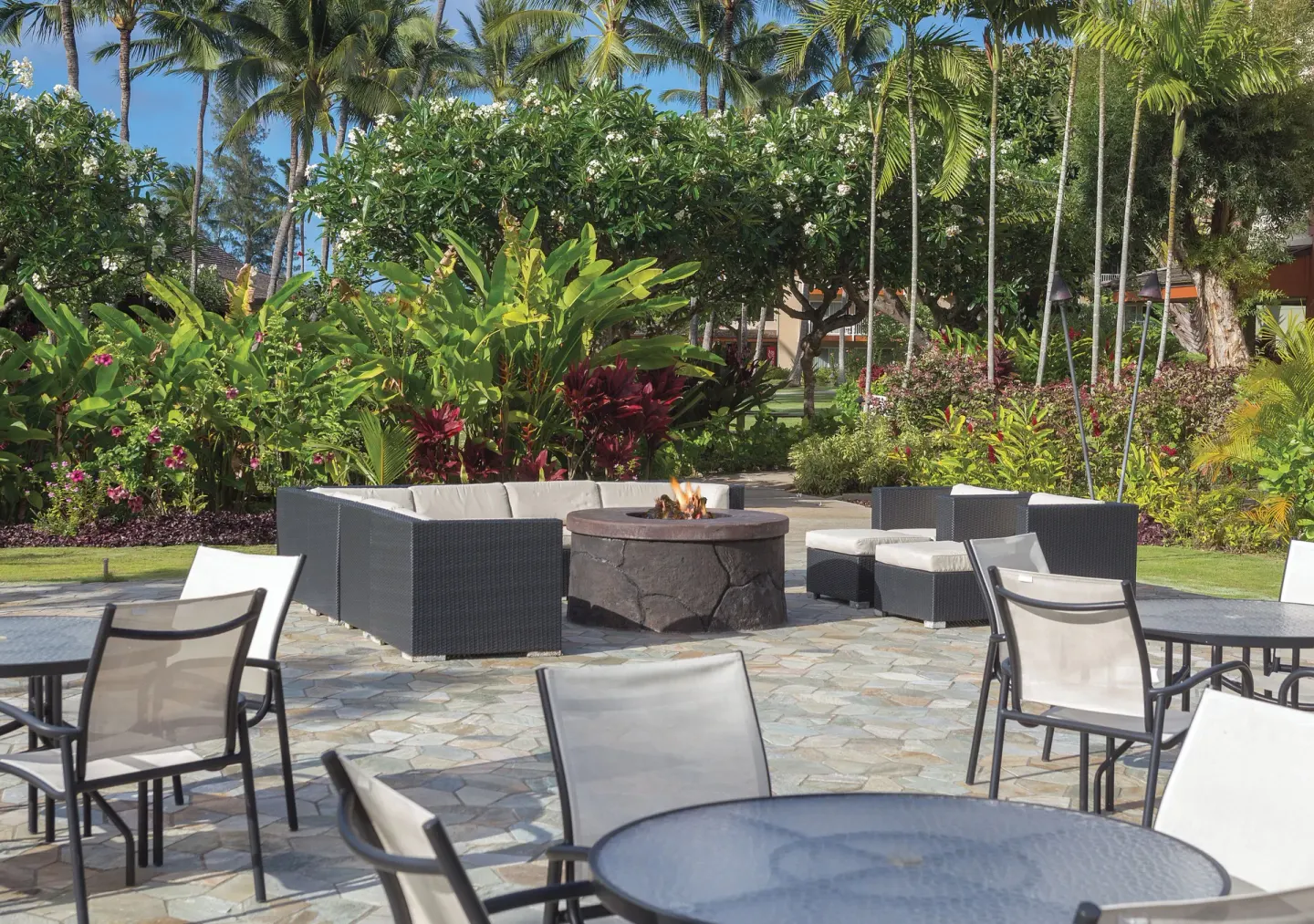Outdoor patio seating with fire pit and tropical plants at Kauai Coast at the Beachboy.