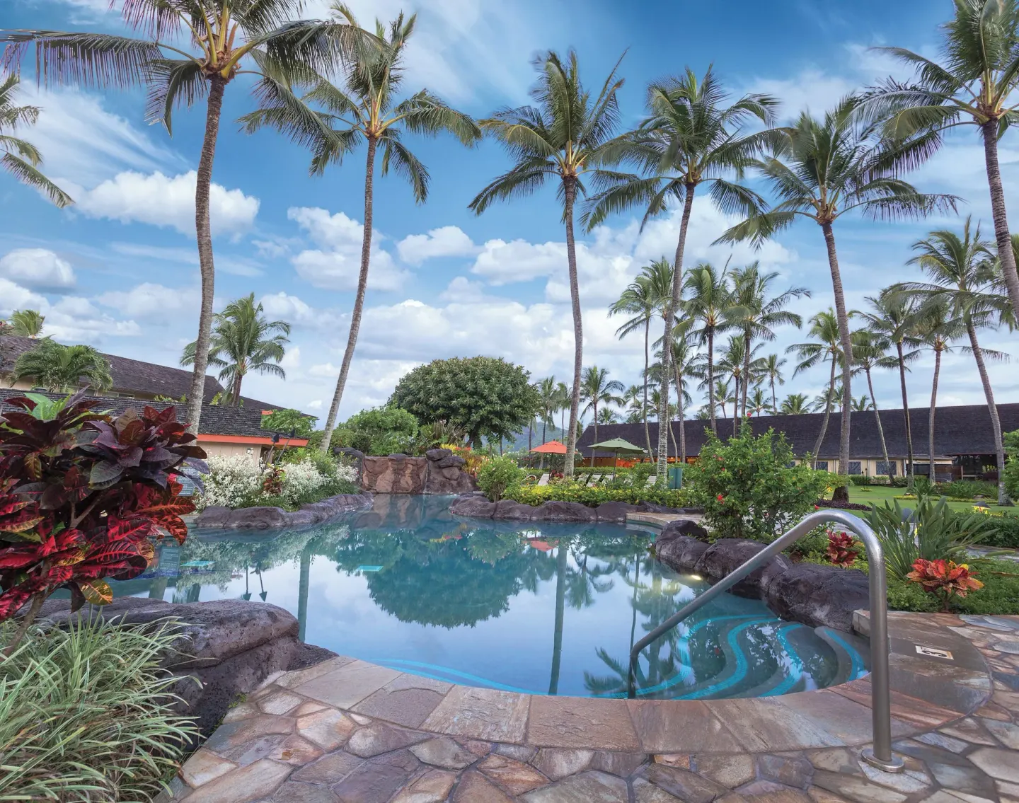 Palm-framed swimming pool and stone deck at Kauai Coast at the Beachboy.