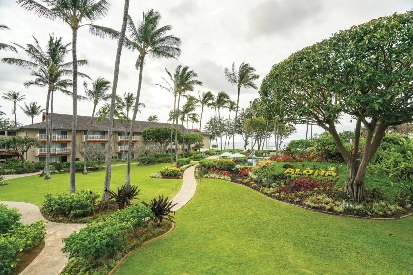Curved garden paths, palms, and resort buildings at Kauai Coast at the Beachboy.
