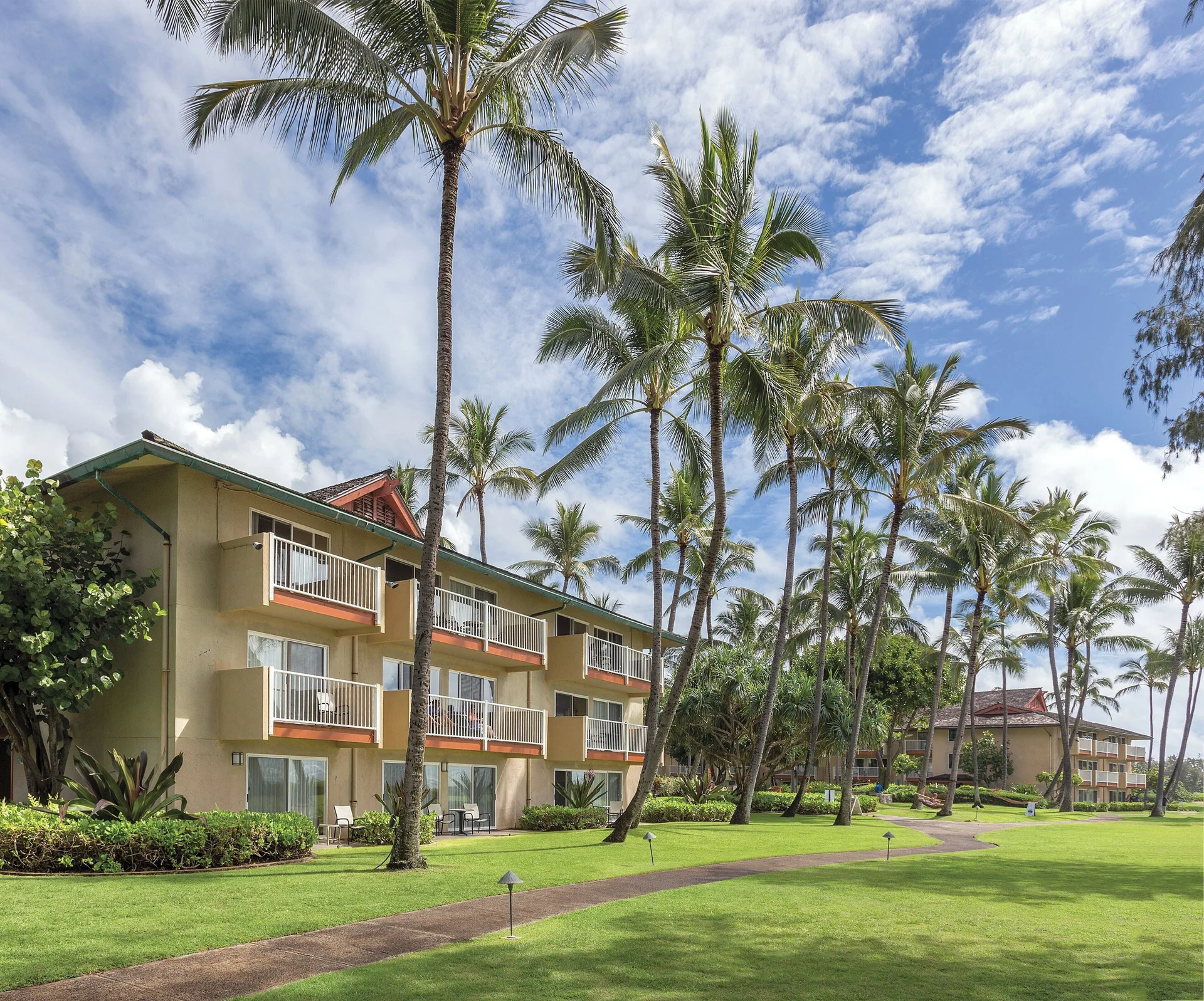 Balconied resort building and palm-lined lawn at Kauai Coast at the Beachboy.