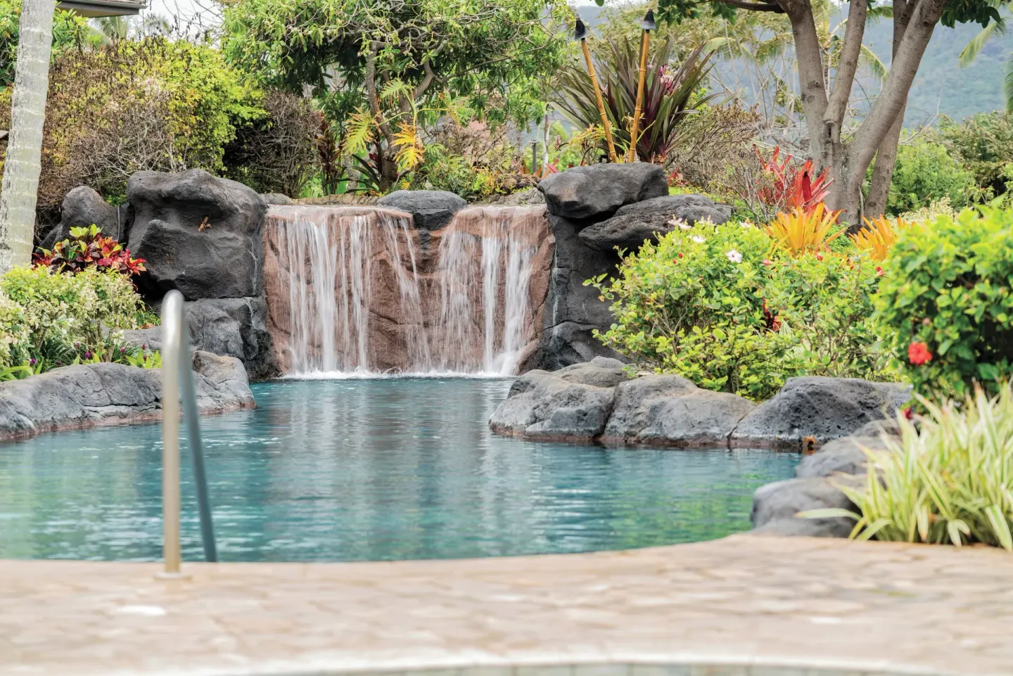 Rock waterfall flows into a landscaped pool at Kauai Coast at the Beachboy.