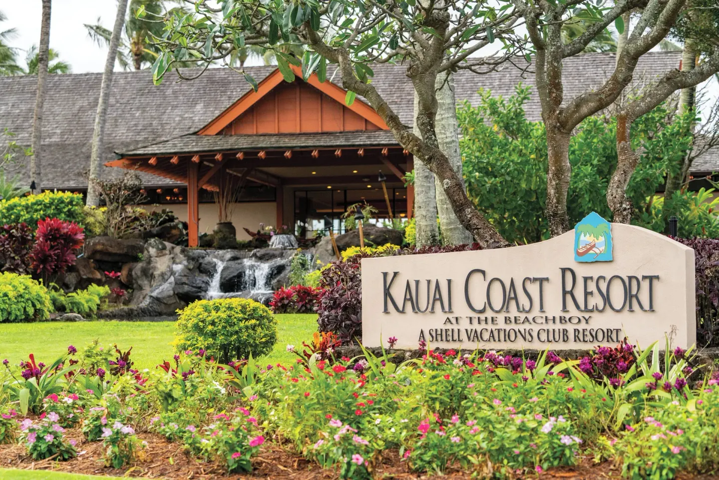 Resort sign with flowers and waterfall at Kauai Coast at the Beachboy.