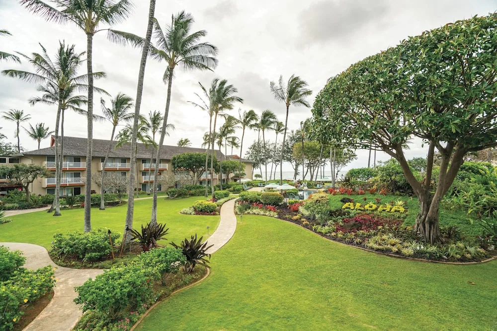 Curving garden paths, palms, lawns, and resort buildings at Kauai Coast at the Beachboy.