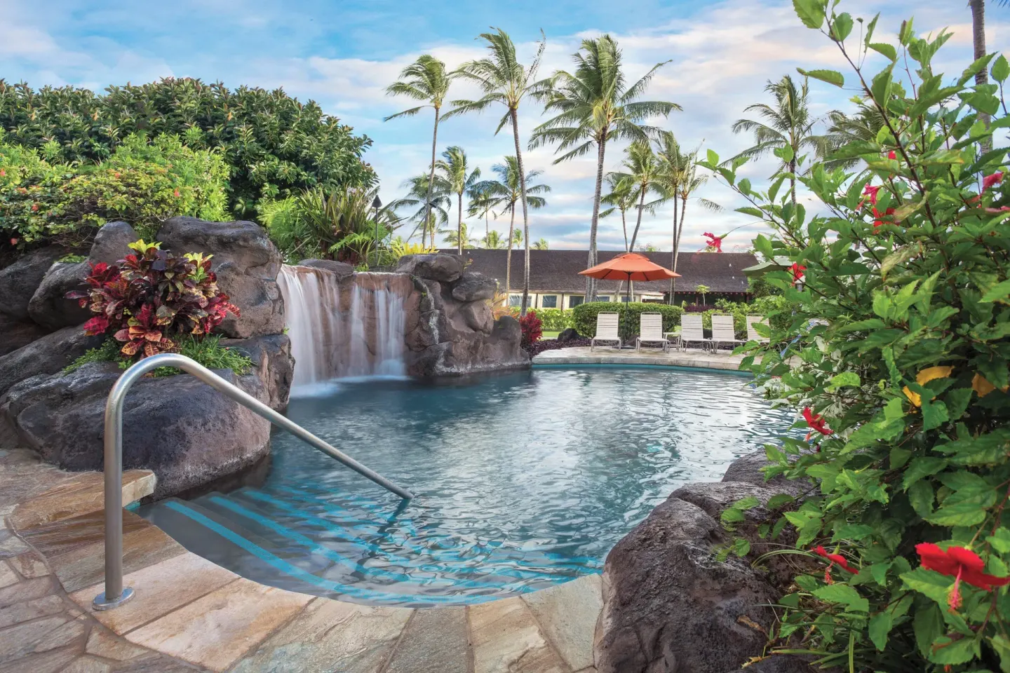 Rock waterfall pool with lounge chairs and palms at Kauai Coast at the Beachboy.