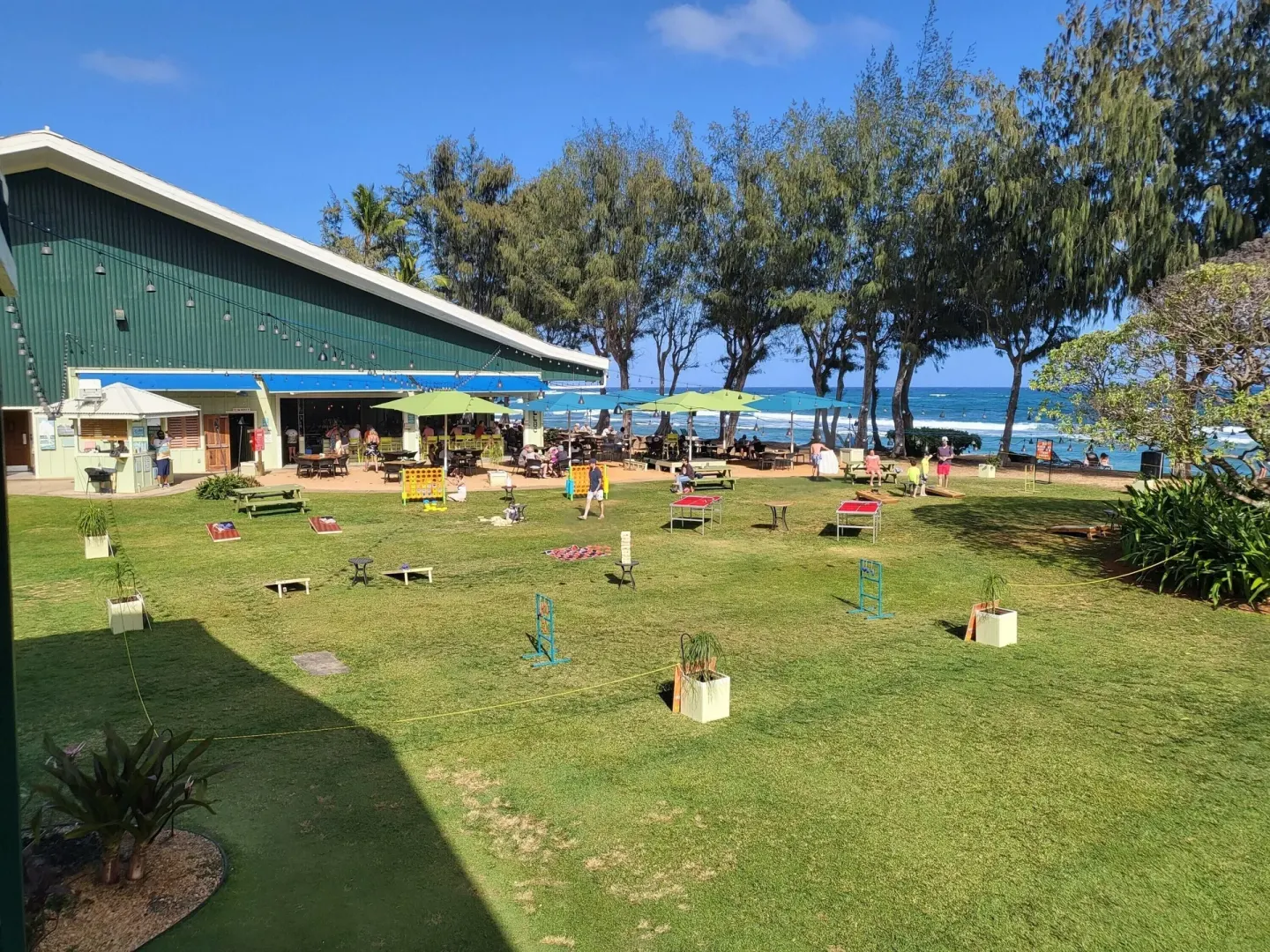 Lawn games, picnic tables, and beachside dining area at Kauai Shores Hotel.