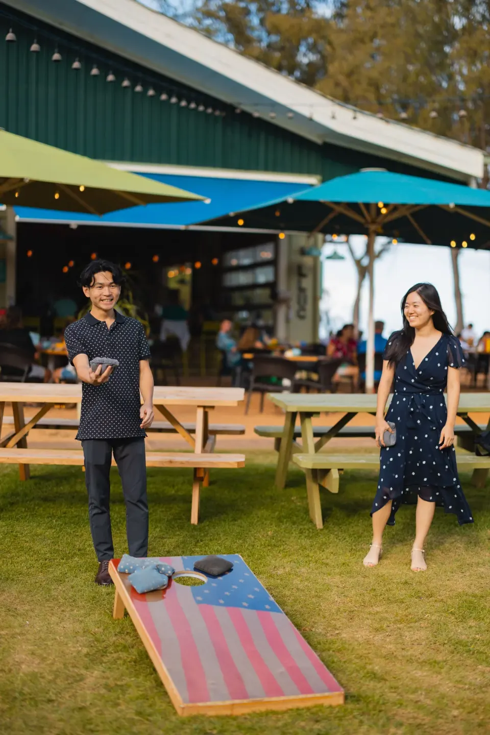 Guests playing cornhole on the lawn near outdoor dining at Kauai Shores Hotel.
