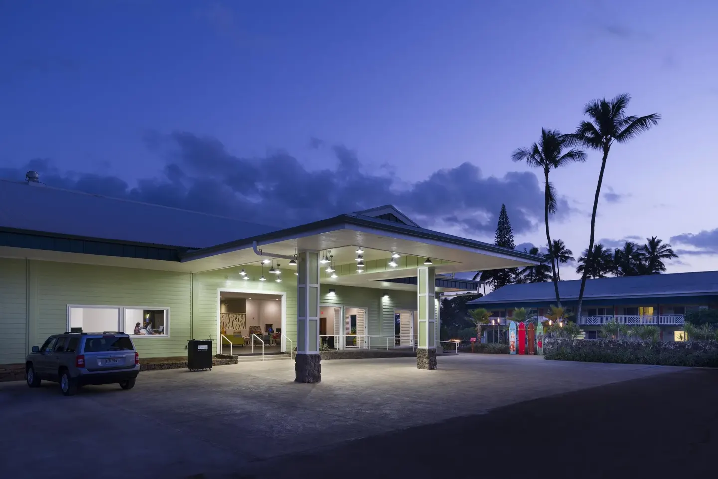 Illuminated hotel entrance and palm trees at dusk at Kauai Shores Hotel.