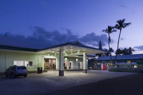Illuminated hotel entrance and palm trees at dusk at Kauai Shores Hotel.