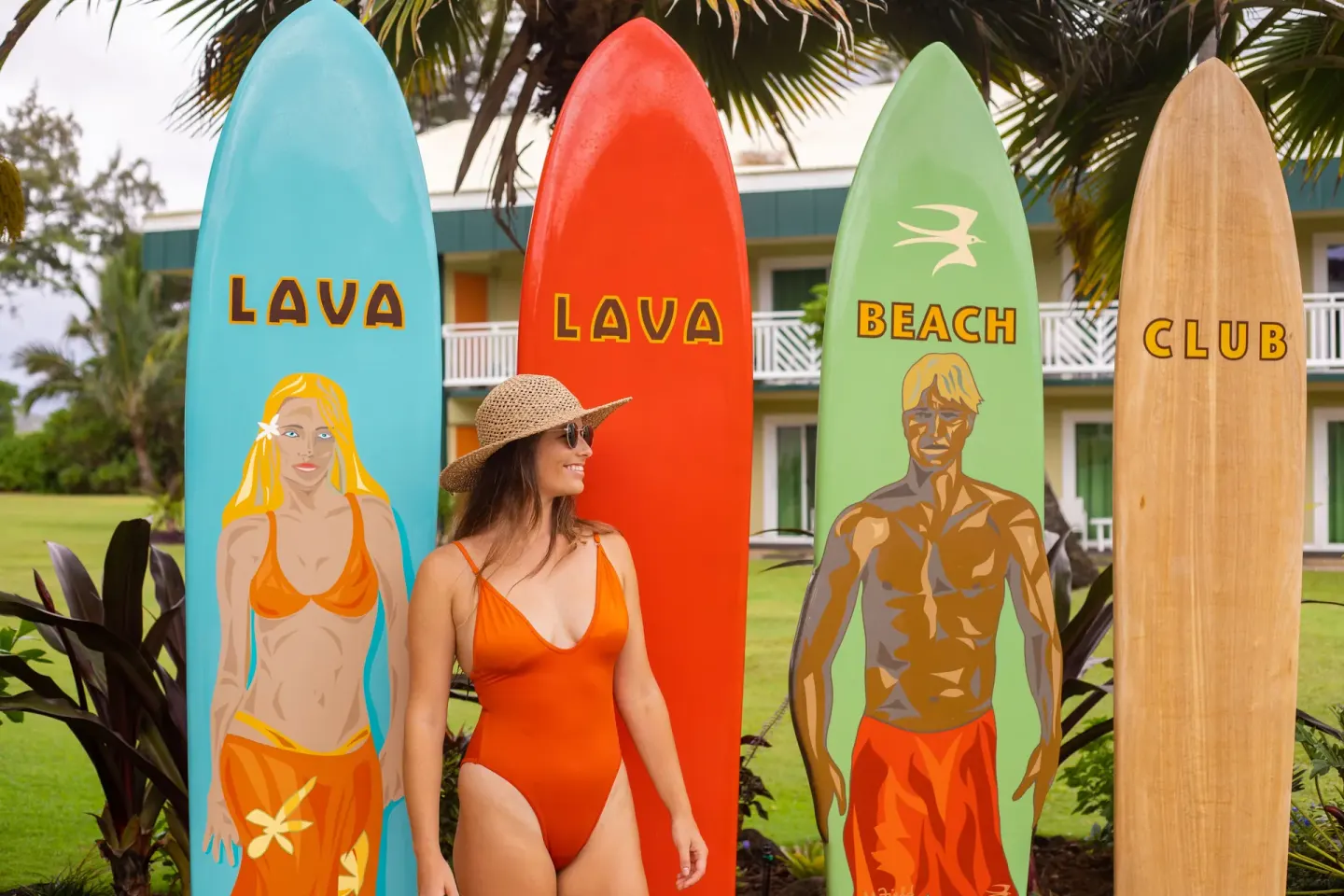 A guest poses beside Lava Lava Beach Club surfboards at Kauai Shores Hotel.