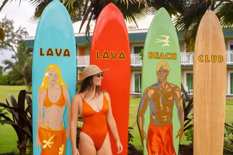A guest poses beside Lava Lava Beach Club surfboards at Kauai Shores Hotel.