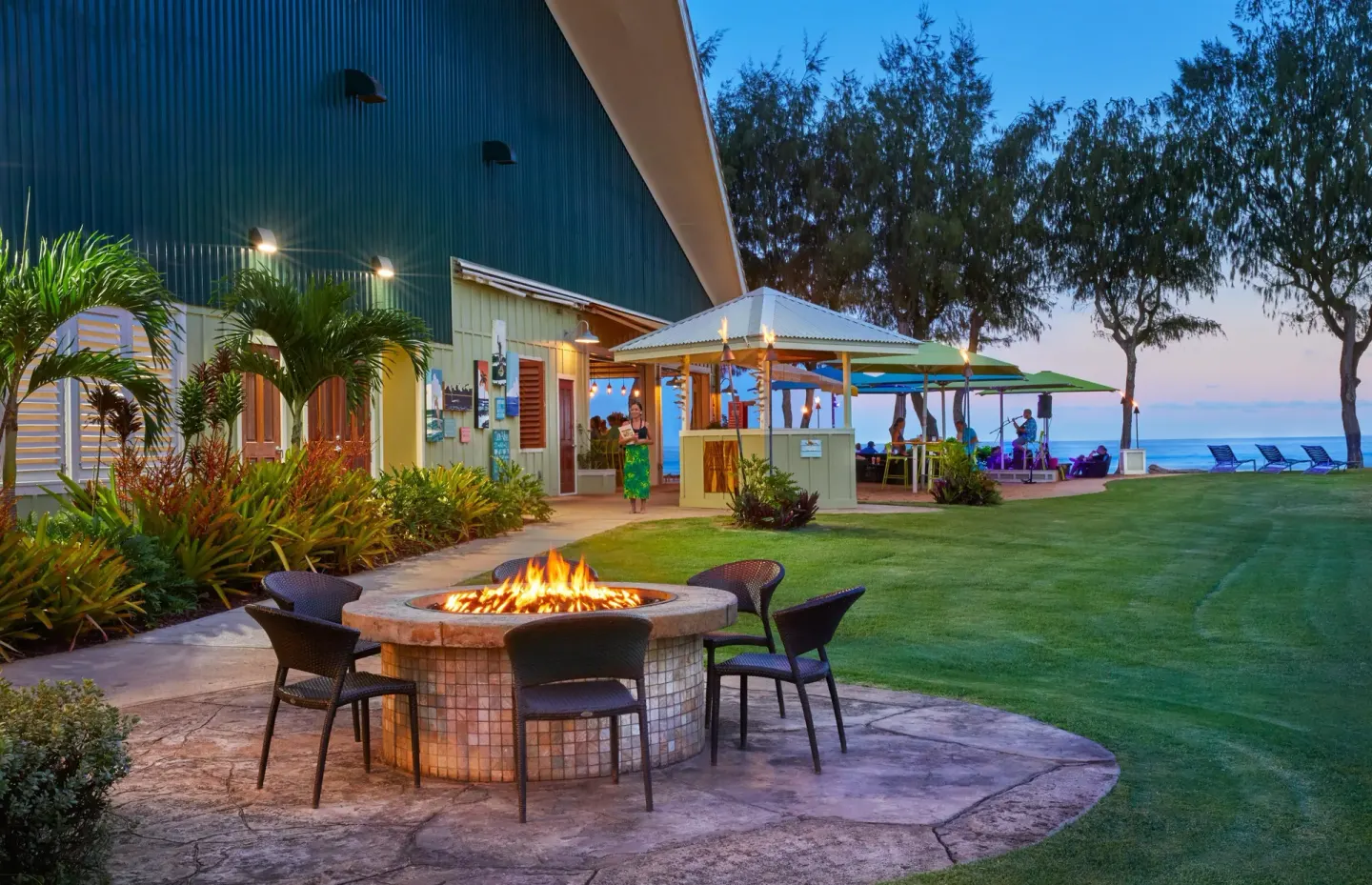 Fire pit seating on the oceanfront lawn at Kauai Shores Hotel at dusk.
