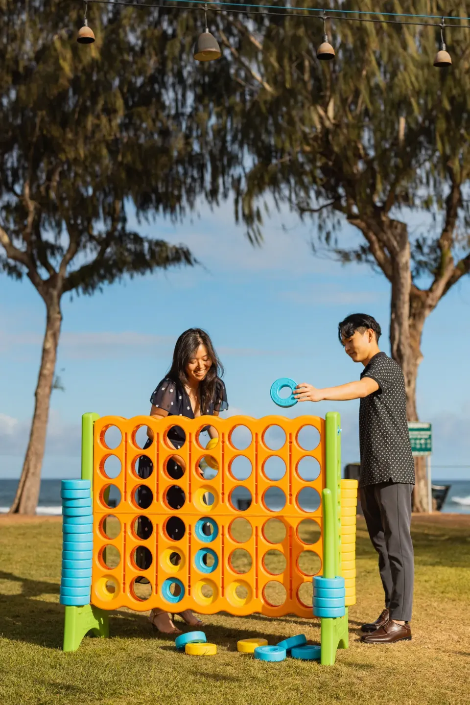 Guests play a giant connect-style lawn game by the ocean at Kauai Shores Hotel.