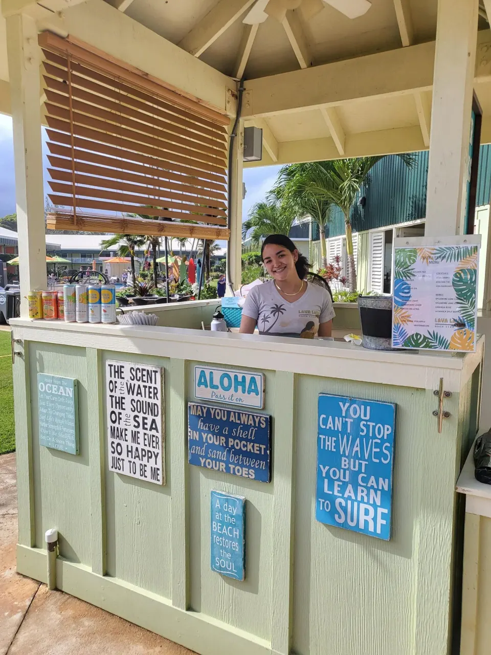 Outdoor service kiosk with beach signs and a staff member at Kauai Shores Hotel.