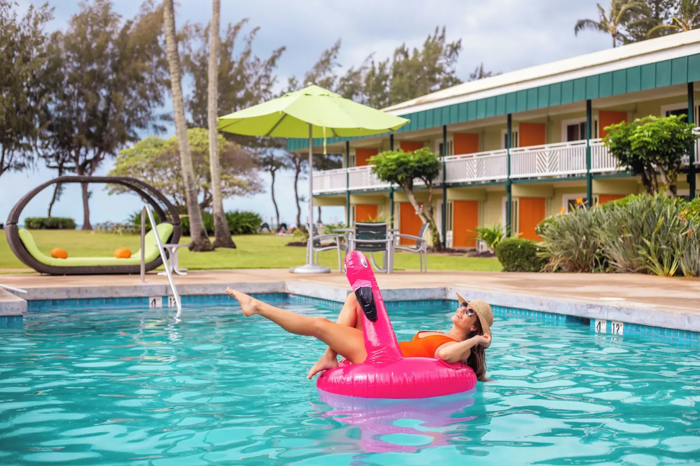 Guest relaxing on a pink flamingo float in the pool at Kauai Shores Hotel.