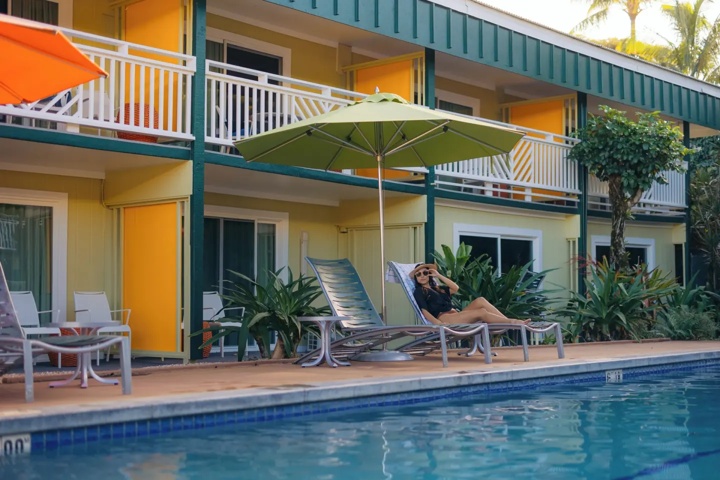 Poolside lounge chairs at Kauai Shores Hotel beside guest room patios and balconies.